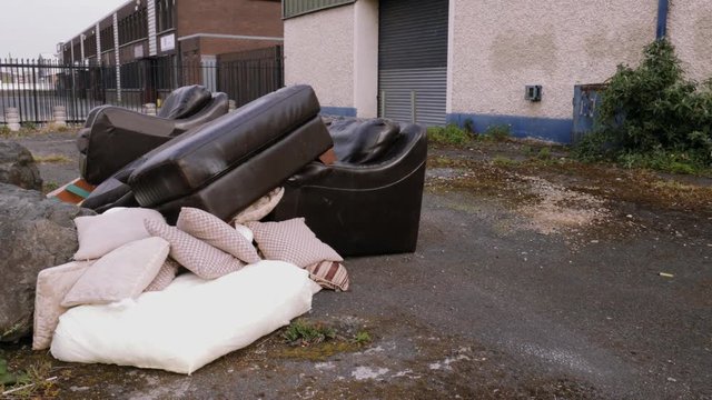 Pan left shot to a pile of used furniture on the street, thrown out used suite of furniture