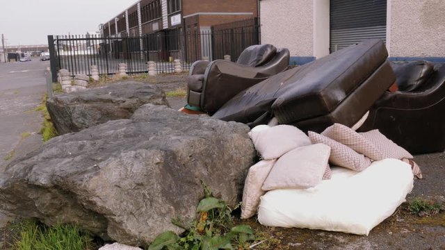 Handheld shot, a pile of garbage, worn out furniture thrown out on the street