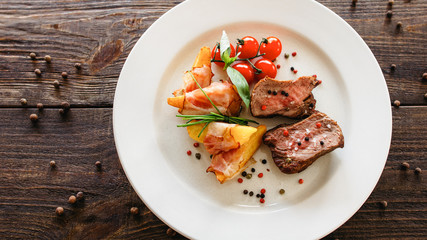 Restaurant catering business. Food presentation. Top view of roasted meat, baked potato with bacon and fresh cherry tomato.