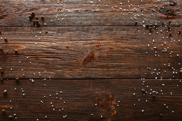 Culinary concept. Rustic wooden background. Top view of scattered sea salt, black pepper, creating...