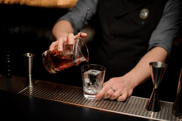 Fototapeta na wymiar Close shot of bartender pouring cocktail using strainer