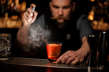 Bartender pours an alcohol cocktail using sprayer