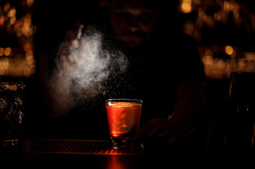Darkened shot of bartender pours an alcohol cocktail using sprayer
