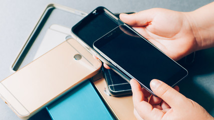 Mobile phone accessories. Cases assortment. Closeup of hands trying new protective cover on smartphone.