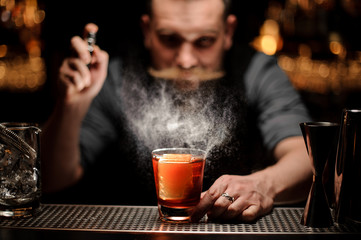 Brutal bartender pours an alcohol cocktail using sprayer