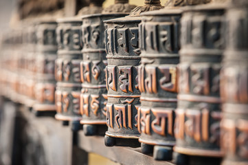 Line of prayer wheels in a village on the Annapurna circuit trail. Buddhist Prayer Mills. Himalayas. Nepal. Asia. Detail of traditional buddhist prayer wheels. Abstract background. Close up.