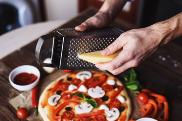men's hands grate cheese for pizza, close up