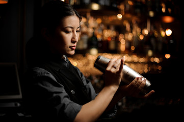Female bartender holding shaker at bar counter