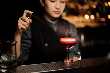 Bartender uses sprayer while pouring alcohol cocktail