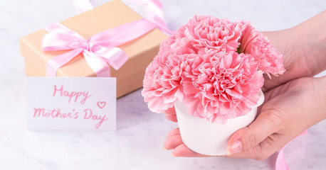 Design concept - Woman giving carnations bouquet on marble white background, top view, copy space, close up, mock up. Mothers day idea inspiration.