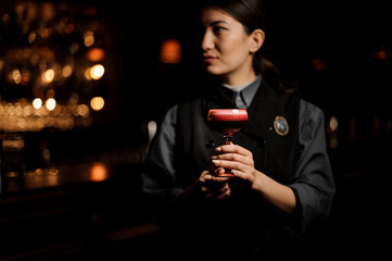 Portrait of female bartender holding red alcohol cocktail