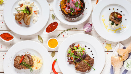 Food assortment top view. Buffet dishes selection on restaurant table. White plates with meals on white background flat lay.