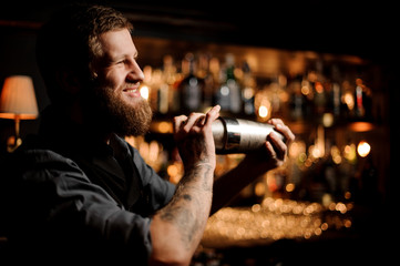 Male bartender uses shaker to prepare an alcohol cocktail