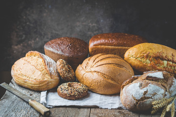 Assortment of fresh baked bread and buns on wooden table background