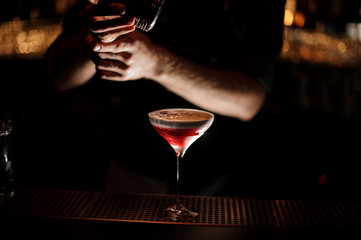 Bartender sprinkles an alcohol cocktail in glass
