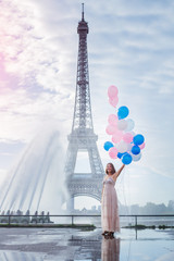 Dream travel - young woman with balloons walking near Eiffel Tower in Paris