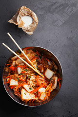 Kimchi Napa spicy pickling cabbages.Korean traditional crunchy spicy fermented vegetables in bowl on dark grey background top view.Probiotic fermented foods concept.Vertical orientation