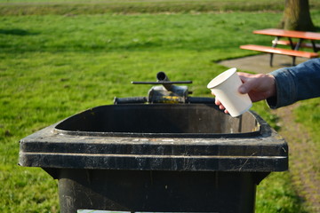 man hand throw white empty cup to the dust bin