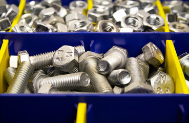 shiny new bolts and nuts in containers, close-up