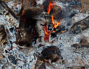 Background of bonfire with glowing red and yellow flame embers. Close up view on smouldering fire.Texture of ash and burning embers. 