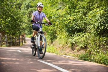 Fototapeta premium Woman cyclist riding Mountain Bike on forest trail