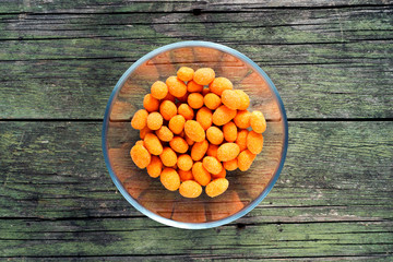spiced coated fried peanuts in glass bowl on wooden background
