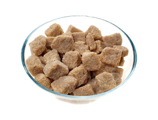 Brown sugar cubes in a glass bowl isolated