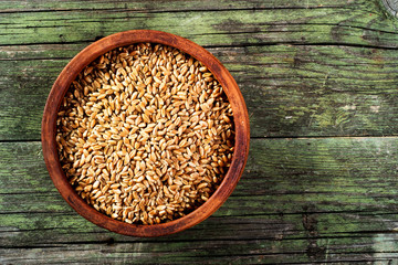 wheat grains and ceramic bowl on wooden table