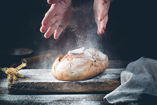 Baker cooking bread. Man slaps flour over the dough. Man's hands Making bread