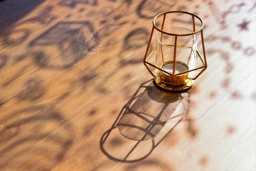 curly shadows on a wooden table on a sunny day, designer candlestick, close-up, selective focus, copy space