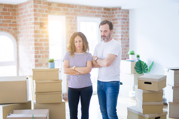 Fototapeta na wymiar Middle age senior couple moving to a new home with boxes around skeptic and nervous, disapproving expression on face with crossed arms. Negative person.