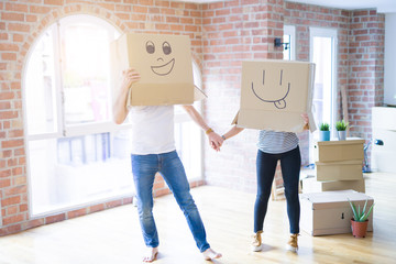 Fototapeta na wymiar Couple wearing funny cardboard boxes with happy faces, moving to a new house, crazy and creative concept