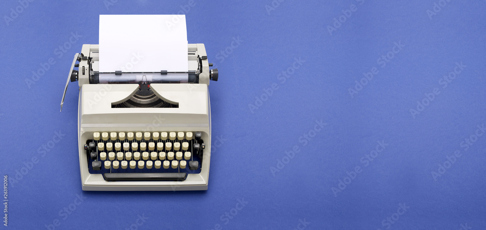 Fototapete top view of a typewriter from the 70s with blank paper for text, isolated on blue background.