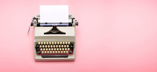 Top view of a typewriter from the 70s with blank paper for text, isolated on pink background.