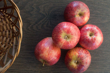 Wooden dark background. Red apples on wooden background, in a basket creating an old and rustic atmosphere. Representation of healthy lifestyle and good health. Flat lay, top view, space for text.