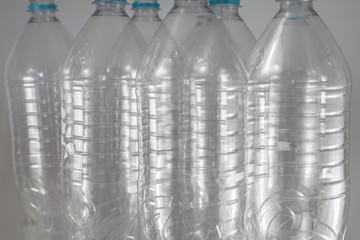 Pack of standing Bottles of a liter and a half of empty mineral water without caps just with the sealing ring on a white background. Reuse, Eco-Friendly, Environment, Conservation, Sustainable