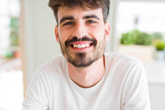 Handsome young man smiling cheerful at the camera with a big smile on face showing teeth