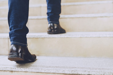 Close up legs shoes of young business man One person walking stepping going up the stairs in modern...