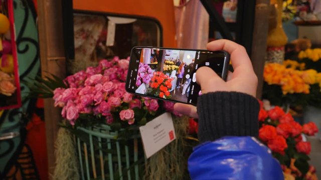 Taking smartphone pictures of beautiful rose flowers in a market