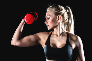 Sports girl pumps biceps with a dumbbell.