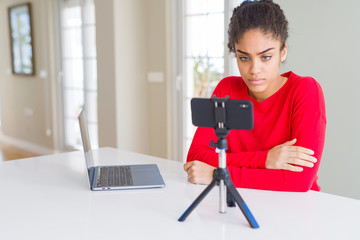 Young african american woman doing video call using smartphone camera skeptic and nervous, disapproving expression on face with crossed arms. Negative person.