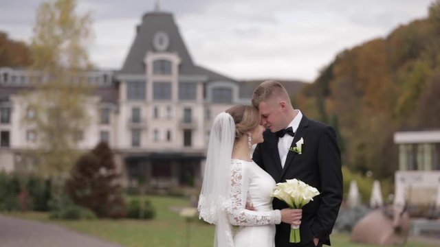 Happy newlyweds walking in the park. Elegant bride and handome groom outside