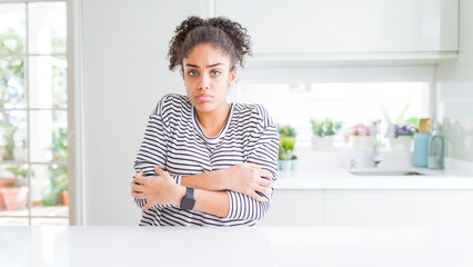 Beautiful african american woman with afro hair wearing casual striped sweater shaking and freezing for winter cold with sad and shock expression on face