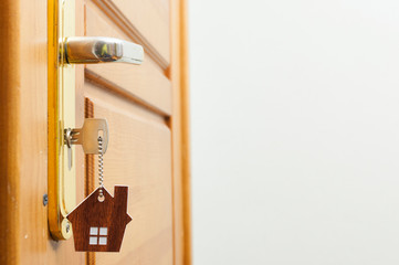 House key on a house shaped silver keyring in the lock of a door
