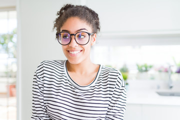 Beautiful young african american woman with afro hair wearing glasses smiling looking side and staring away thinking.