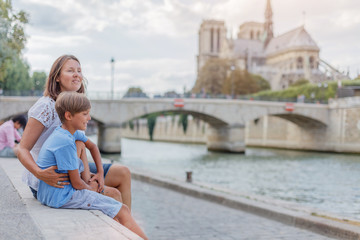 Happy mother and her son having fun near Notre-Dame cathedral in Paris. Tourists enjoying their vacation in France.