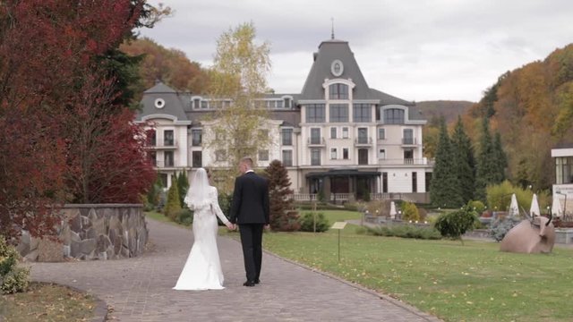 Happy newlyweds walking in the park. Elegant bride and handome groom outside