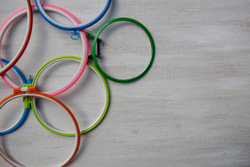 Multicolored plastic embroidery hoops for creative art on a light background. View from above.