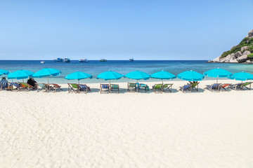 Row of blue parasols with wooden beach chairs on tropical sandy beach in sunny day at Koh Nang Yuan Island Surat Thani, Thailand     