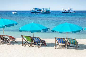 Row of blue parasols with wooden beach chairs on tropical sandy beach in sunny day at Koh Nang Yuan Island Surat Thani, Thailand     